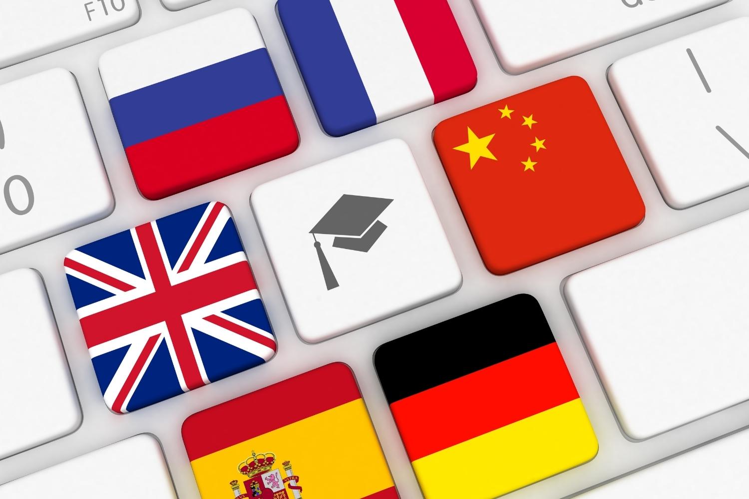 on the keys of a keyboard, flags of different countries lined up around a graduation cap